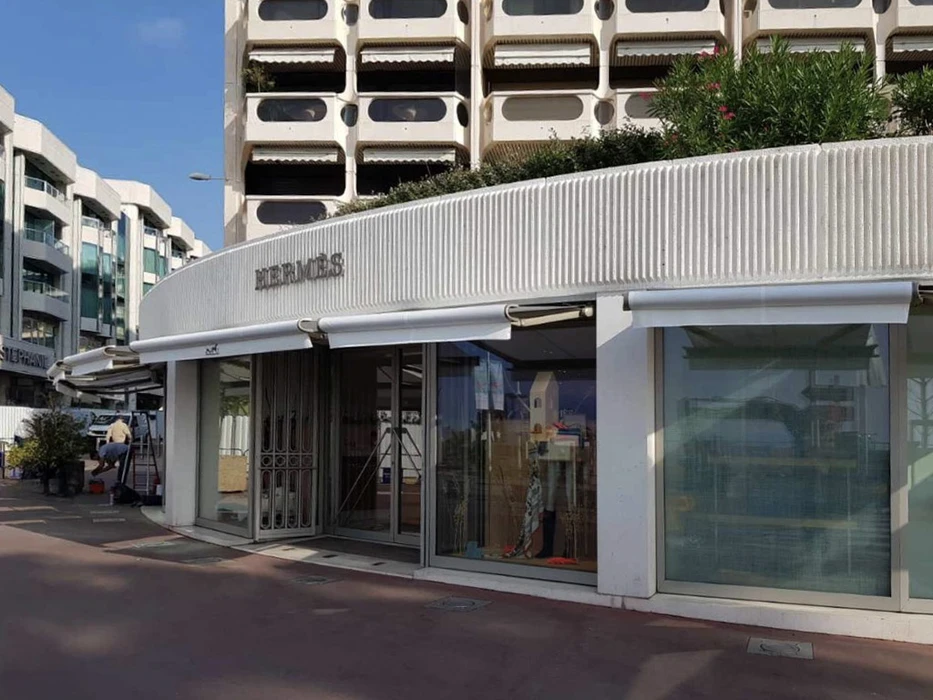 Terrasse extérieure d'une villa avec piscine, équipée d'une table et chaises sous store banne orange déployé